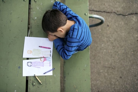 Boy looking sad at drawing of a broken family